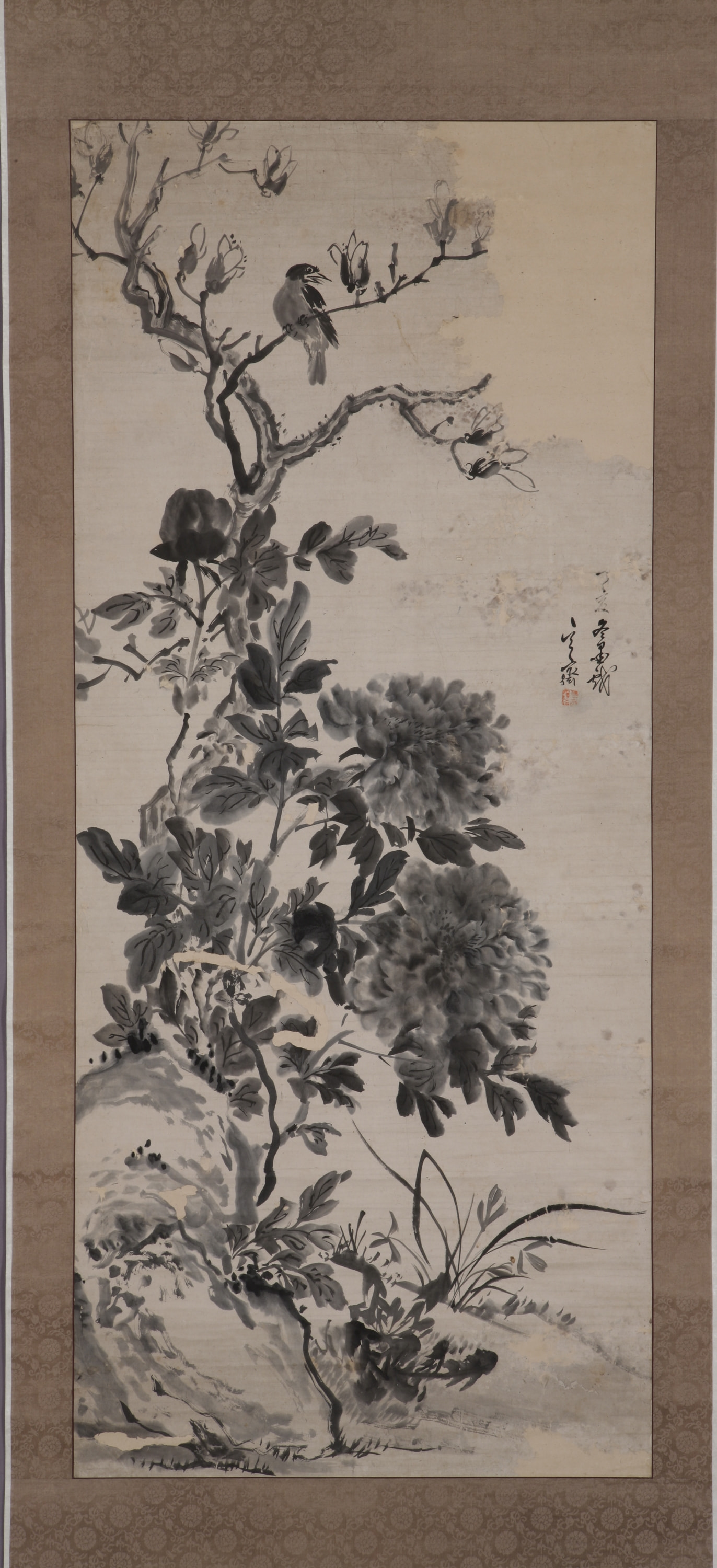 A twisted branch rises from a slight hill and contains lush flowers. A bird sits on the top branch