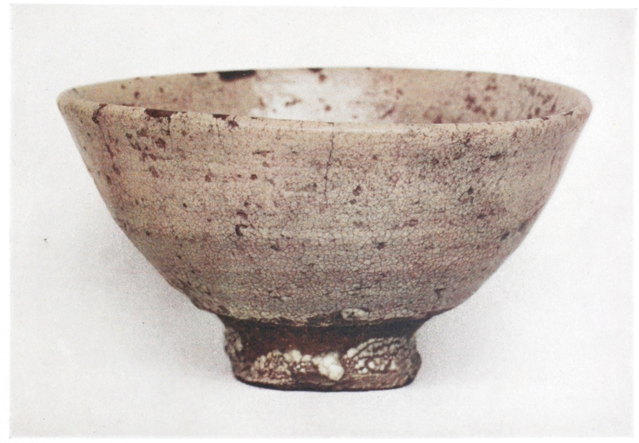 This bowl rests on a thin brown base and flares out to a thin lip. The body is mottled white over brown, and the lip is not perfectly aligned.