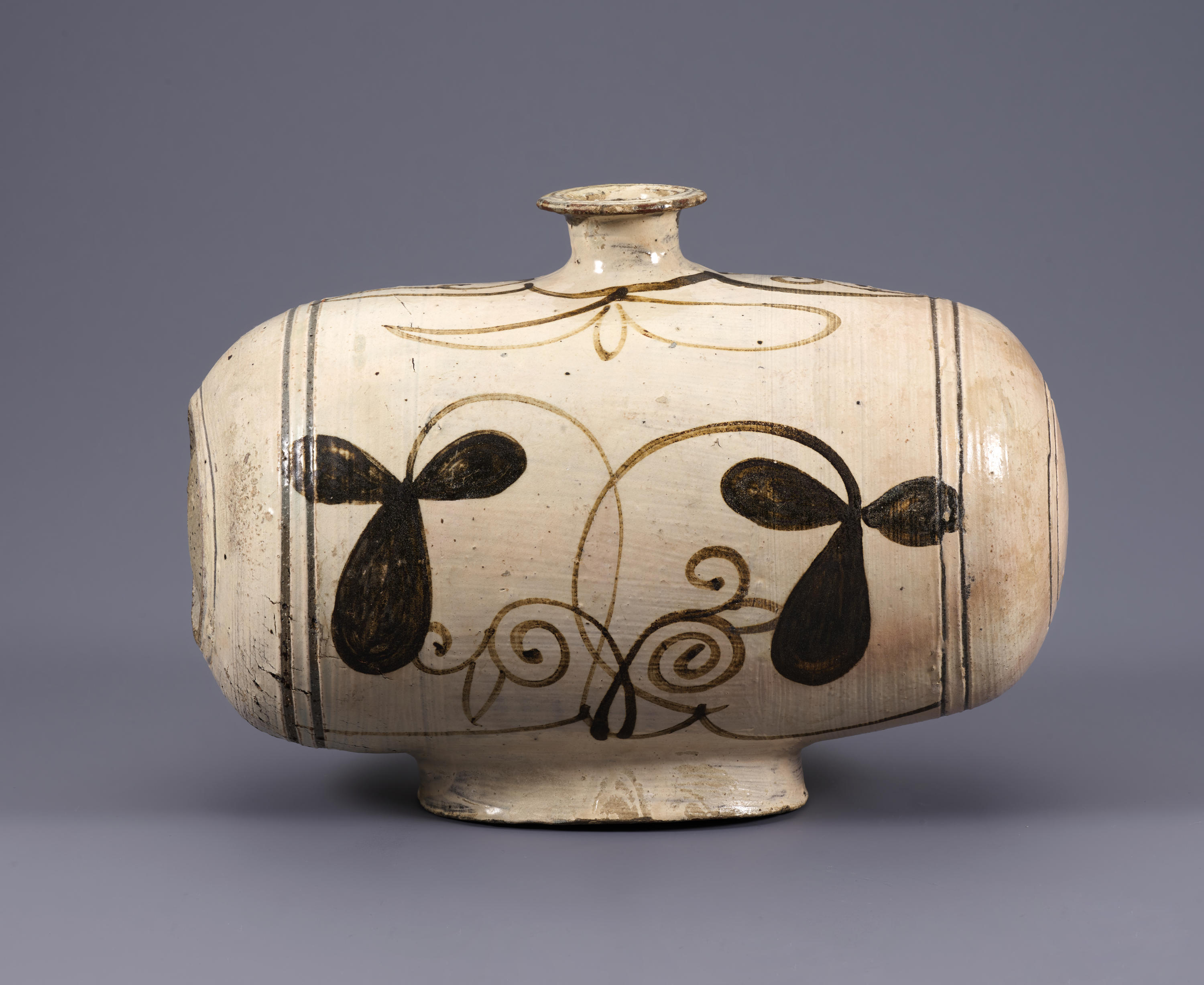 The central register of this wide, round vessel features dark, abstracted flower petals and swirling brown lines. The body rests on a narrow base and has a narrow, flared opening at top center.
